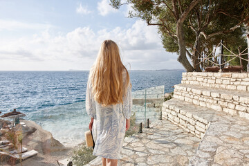 Blonde woman in summer dress at a sea resort - obrazy, fototapety, plakaty
