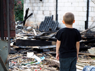 a little boy in a black T-shirt and pants stands with his back against the background of a...