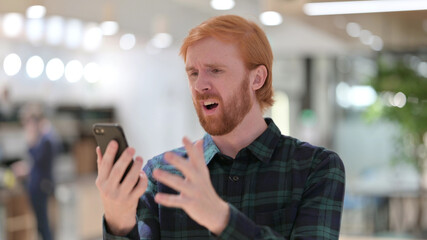Portrait of Redhead Man Reacting to Failure on Smartphone 
