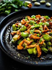 Broad beans salad with fried chanterelles, garlic and parsley on wooden table
