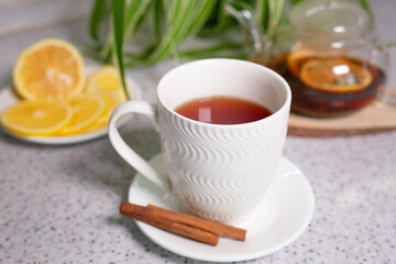 A hot tea drink with lemon and orange, a teapot and a white cup, served with delicious lemon and cinnamon. Fragrant and warming tea. Step 4