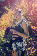 sexy female soldier is using the binoculars at nature