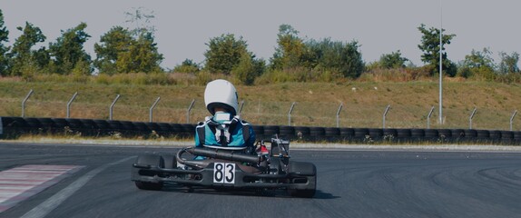 Back view of teenager professional racer driving his go kart on a race track - obrazy, fototapety, plakaty