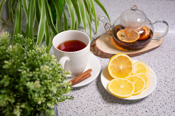 A hot tea drink with lemon and orange, a teapot and a white cup, served with delicious lemon and cinnamon. Fragrant and warming tea. Step 6