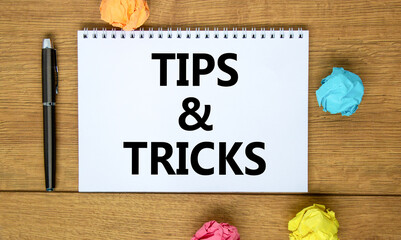 Tips and tricks symbol. Words 'Tips and tricks' on white note on beautiful wooden table, colored...