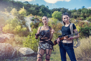 two beautiful young women with firearms in nature - obrazy, fototapety, plakaty