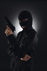 Woman wearing knitted balaclava with gun on black background