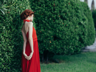 woman in red dress elegant style garden nature posing