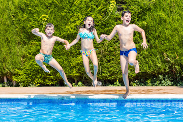 Three kids jumping into a pool in a sunny day