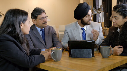 Sikh turbaned team leader discussing an important matter among his team members