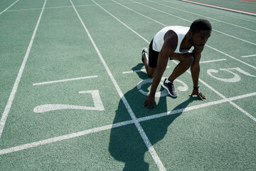 African American male athlete stands at the start preparing for the race. Sport competitions
