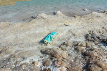 Fototapeta na wymiar Protective masks contaminate the Dead Sea shore