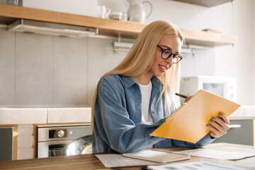 Young blonde woman in glasses studying working