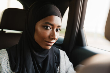 Black muslim woman looking at camera while going in car