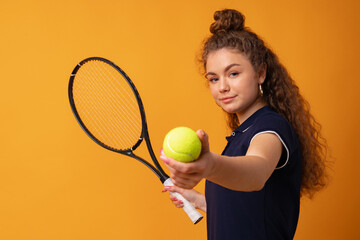 Young woman tennis player standing with racket against yellow background