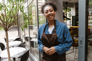 Black waitress wearing apron standing while working in cafe outdoors