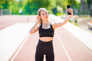 Beautiful young fitness woman taking selfie outdoors