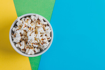 Bowl with popcorn on a colourful background. Concept film genres.