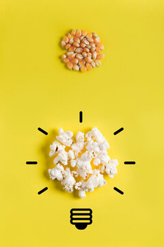 Corn kernels and popcorn with light bulb drawing on yellow background.