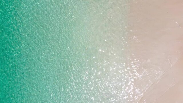 Aerial view shot of drone. Top-down view full frame beach sand and water texture and clear. Nature and travel concept. 4K UHD Video clip.