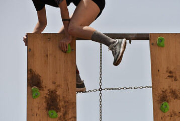 Participant in extreme obstacle race climbing over hurdle - Powered by Adobe