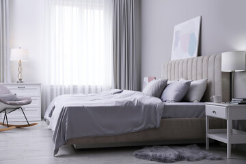 Cozy bed with soft silky bedclothes in light room