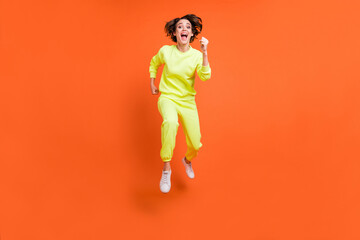 Fototapeta na wymiar Full length body size view of attractive cheerful motivated girl jumping running marathon isolated over bright orange color background