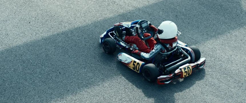 Teenager professional karting racer closing visor and starting his kart on a racetrack. Shot with 2x anamorphic lens