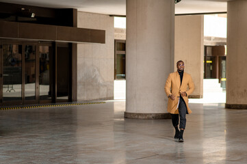 Full length portrait of young black businessman walking in the city.