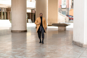 Full length portrait of young black businessman walking in the city.
