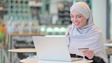Arab Woman making Online Payment on Laptop with Credit Card 