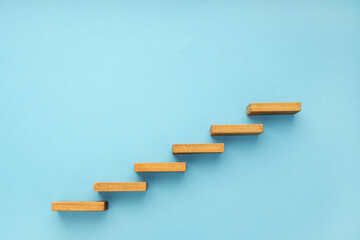 Wooden staircase on blue background. Growth, increasing business, success process concept. Copy space - obrazy, fototapety, plakaty
