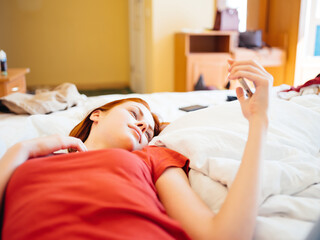 woman lies on the bed with a phone in her hands leisure lifestyle
