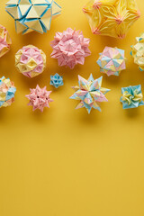 Set of multicolor handmade modular origami balls or Kusudama Isolated on yellow background. Visual...