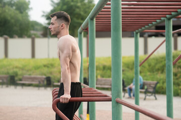 Obraz premium Young attractive Caucasian man doing push ups on the bars. Workout concept
