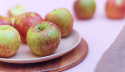 On a pink background in a plate of ripe apples close-up