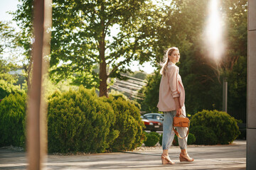 Stylish young businesswoman walking on the city street on sunny day