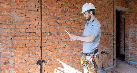 An electrician contractor examines a blueprint at a construction site.