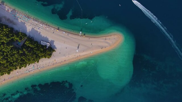 Aerial view of the Zlatni Rat sandy beach and sailing boat in Adriatic sea on Brac island, Croatia. 4k drone video. Top view. Summer vacation resort