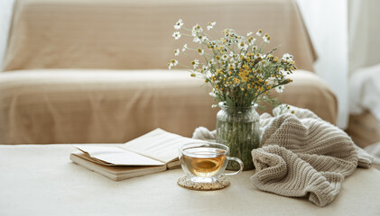 Cozy home composition with a cup of tea, a book and flowers copy space.