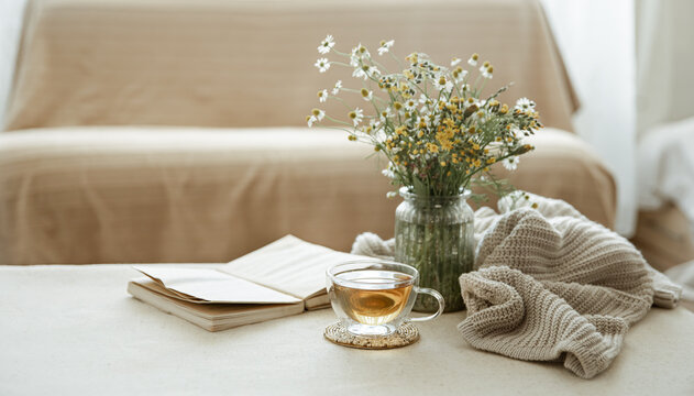Cozy home composition with a cup of tea, a book and flowers copy space.