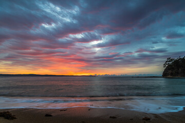 Obraz premium Cloud covered sunrise seascape tinged with pink