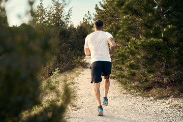 Young muscular male athlete running up the hill