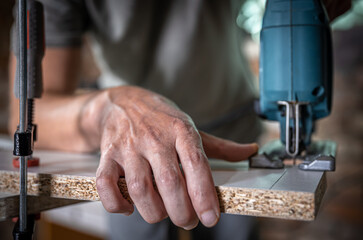 Close-up process of cutting wood board with jigsaw.