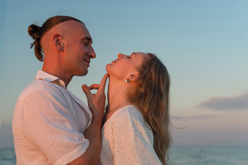 Obraz premium happy beautiful couple walking at sunset along the seashore