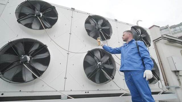 Technician uses a thermal imaging infrared thermometer to check the condensing unit heat exchanger