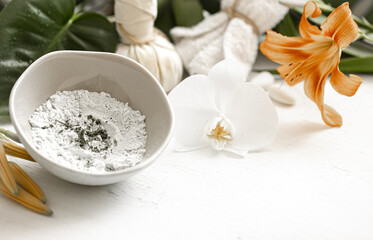 Spa composition with powder face mask and flowers.