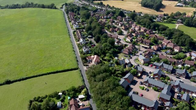 4K drone footage of a housing estate with a road nad farmland next to it.
