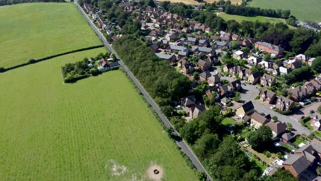 4K drone footage on a country road between a housing estate and farmland