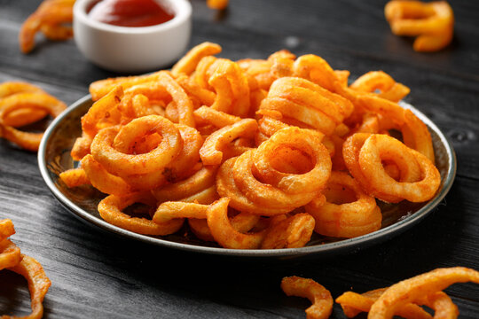 Golden Curly Fries with ketchup on rustic plate